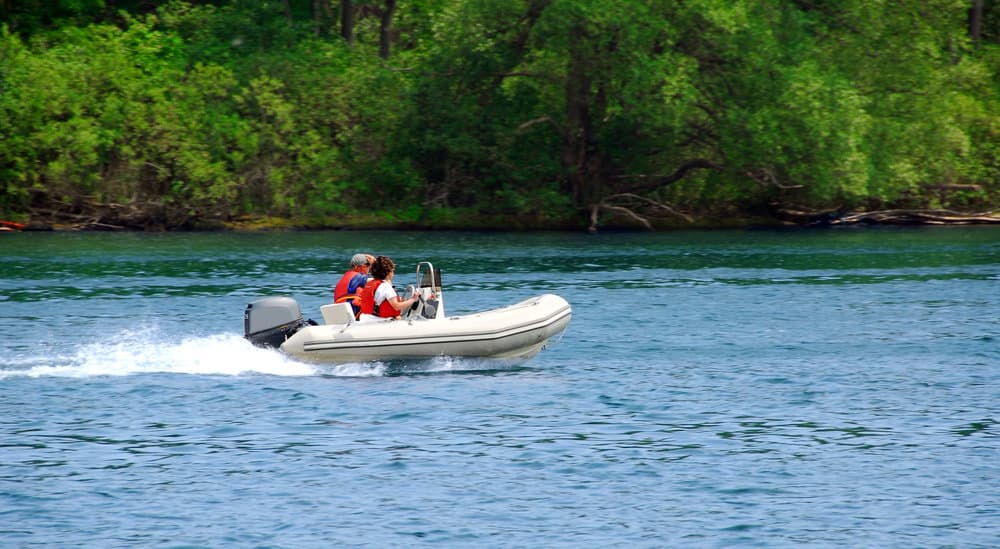 couple driving hard bottom inflatable boat on a river