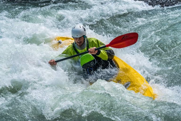 man in inflatable boat kayaking on white water