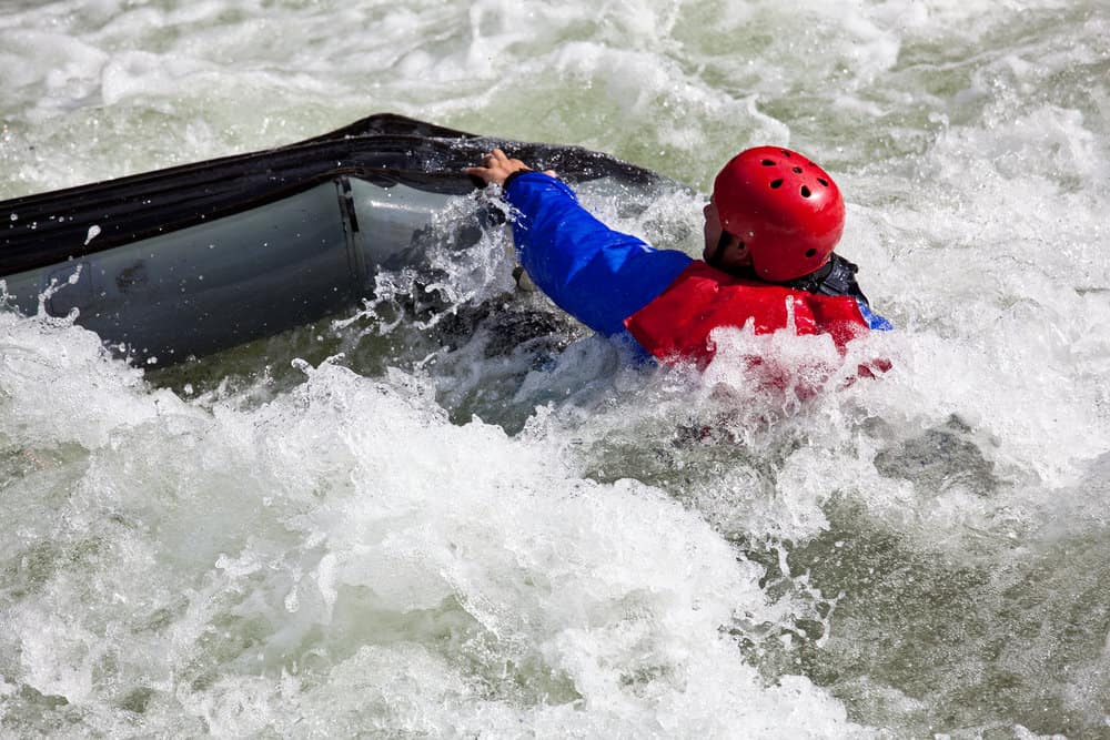 man sinking in white water while kayaking