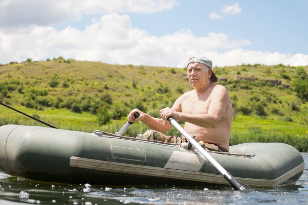 senior man rowing an inflatable boat on a lake