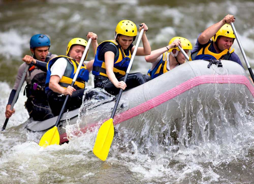 inflatable boat carrying a group of five people rafting on white water