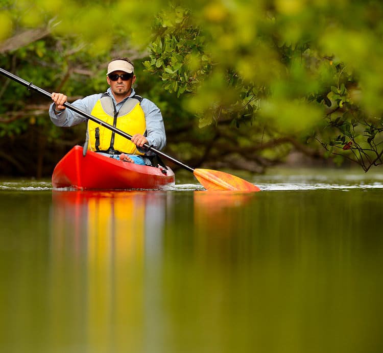 man rowing on a river with a long paddle