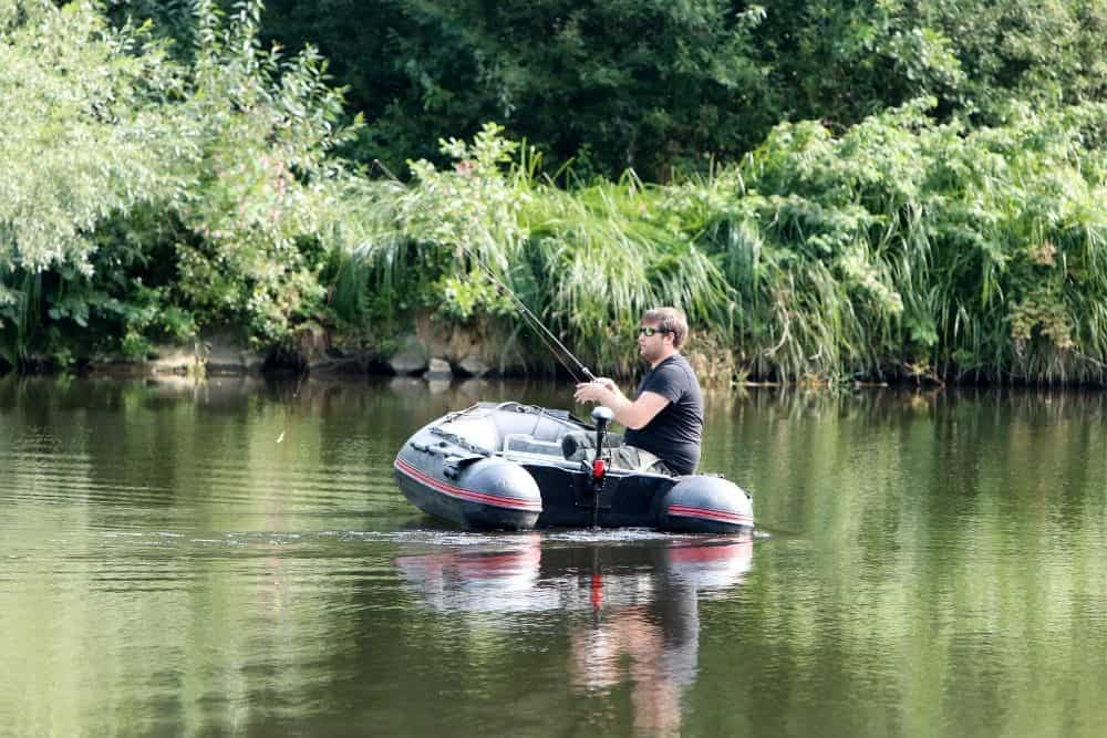 young man on inflatable boat fishing with trolling motor