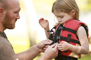 A man putting a life jacket on a child