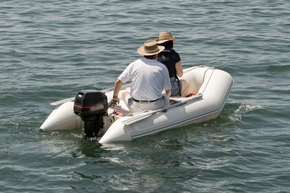 a couple in an inflatable boat using outboard motor