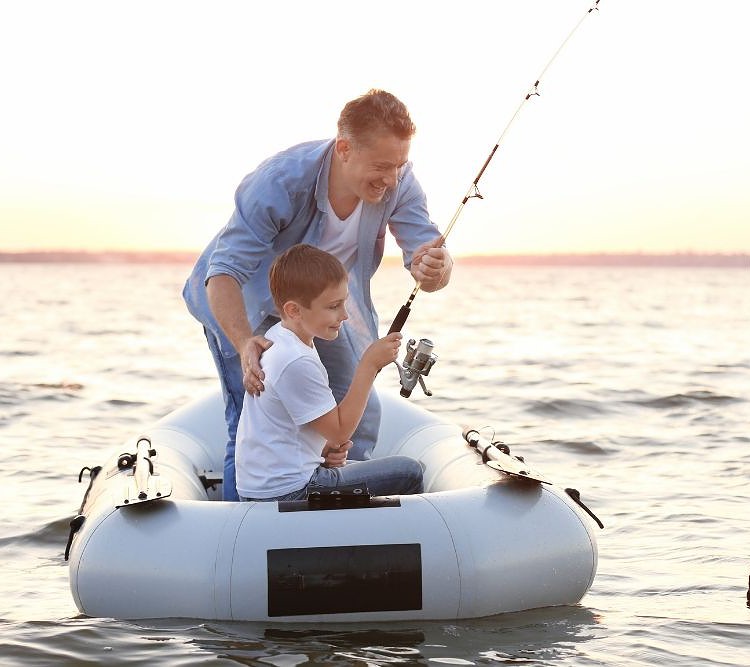 dad and son are fishing on a lake with a white inflatable boat