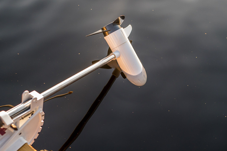propeller of a white electric trolling motor is floating on the water surface