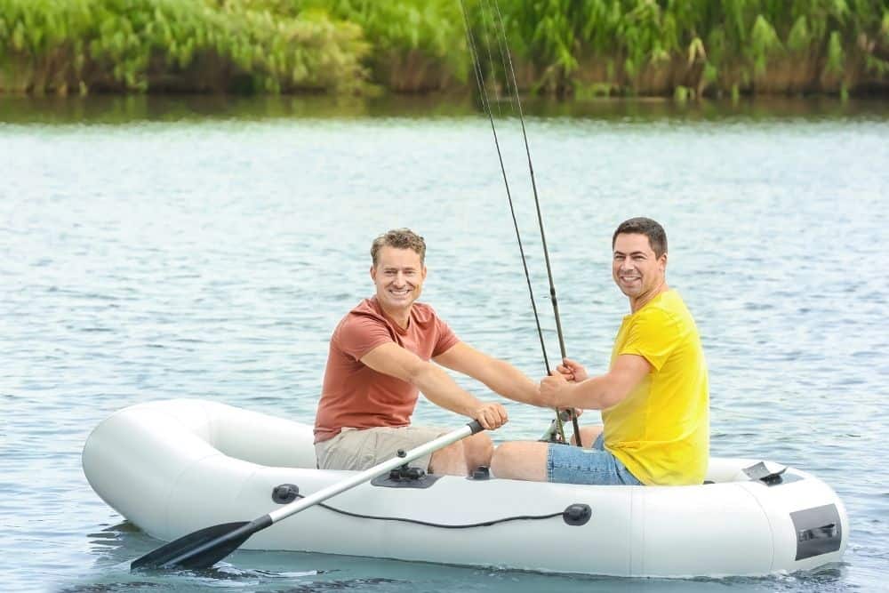 two men are fishing on a white inflatable boat