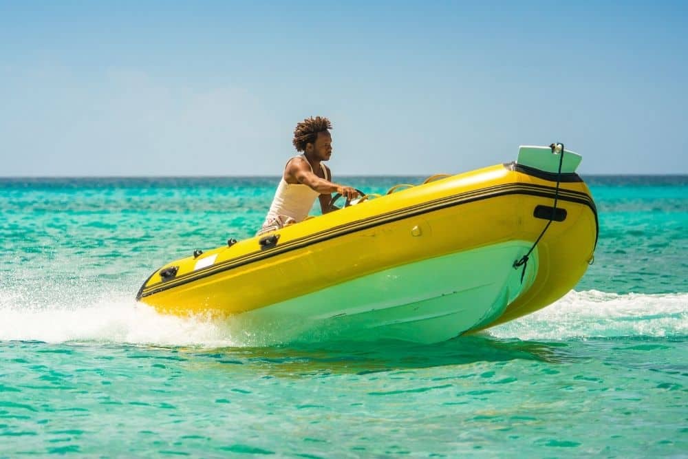 a black man driving a yellow RIB with heavy hull on ocean