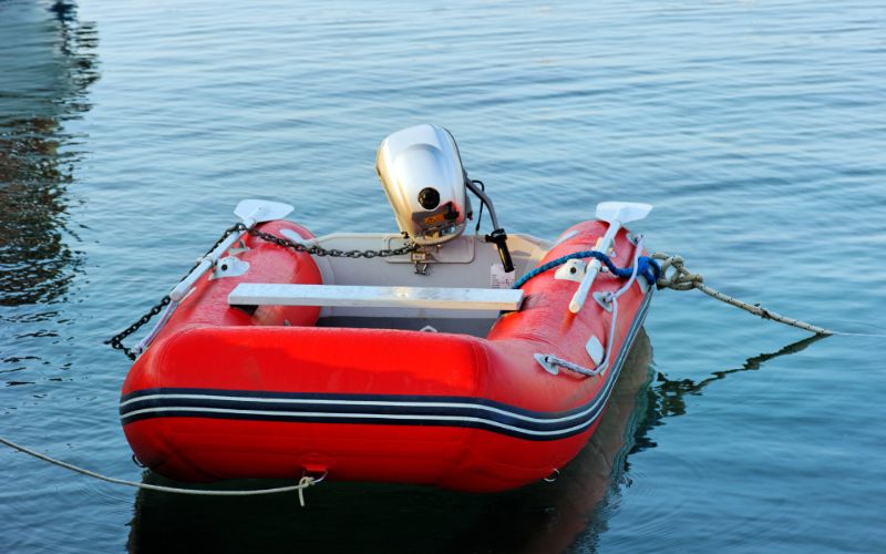 red inflatable boat with outboard engine anchored