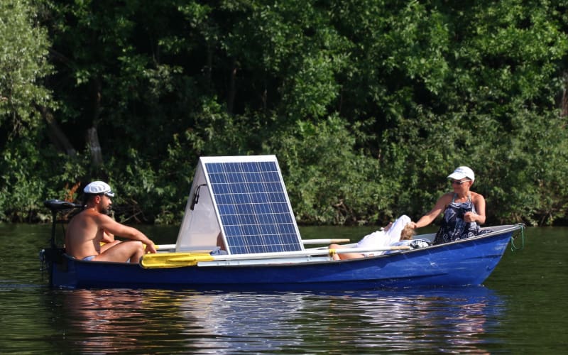 the couple enjoys their trip on a canoe with a transom mount trolling motor and solar panels floating along a forest river