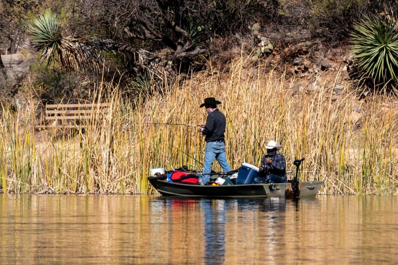 two men go fishing on a jon boat with trolling motor