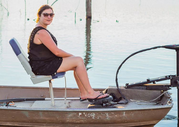 woman sits on a jon boat using foot pedal to control trolling motor