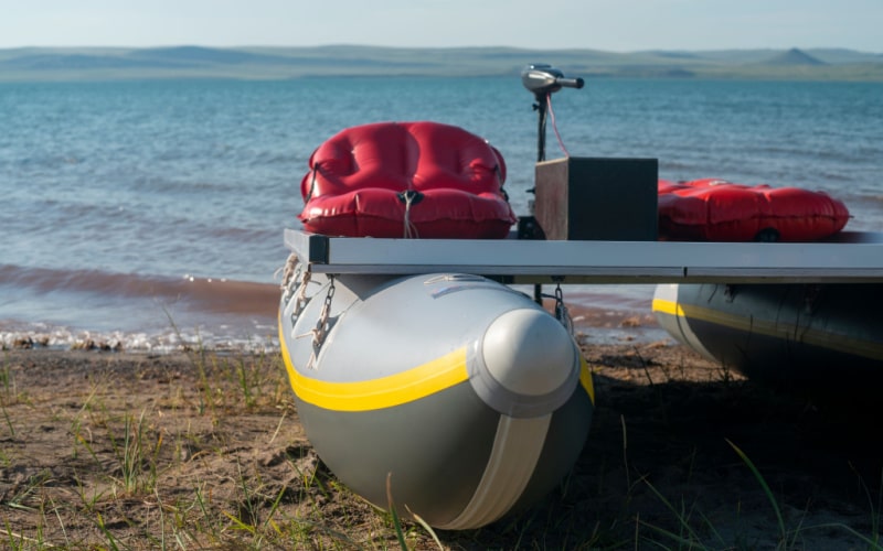 trolling motor with battery on an inflatable pontoon boat by the lake