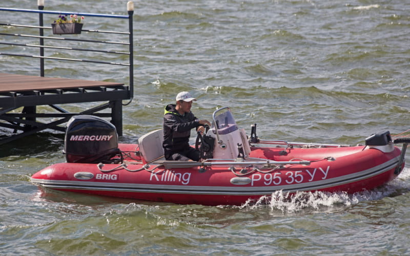 Man on a red Brig RIB with Mercury outboard motor running on a river