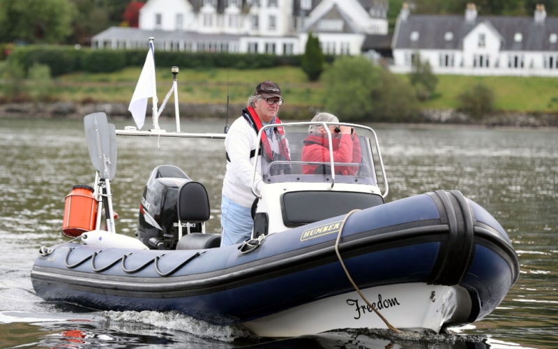 elderly couple on the big black rib with a Suzuki outboard motor on a river