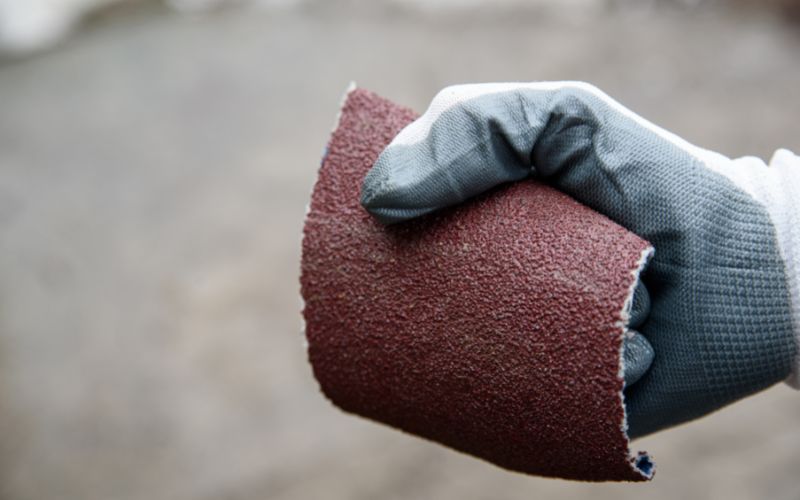 hand holding a piece of sandpaper