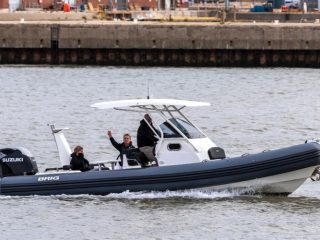 three people on a big Brig RIB equipped with an Suzuki outboard motor moving along a harbour