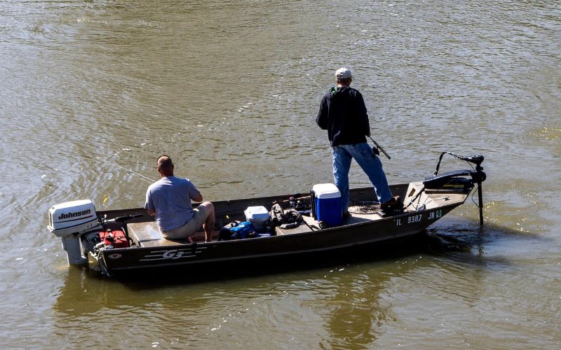 two anglers are fishing in a river in a nice weather and calm water