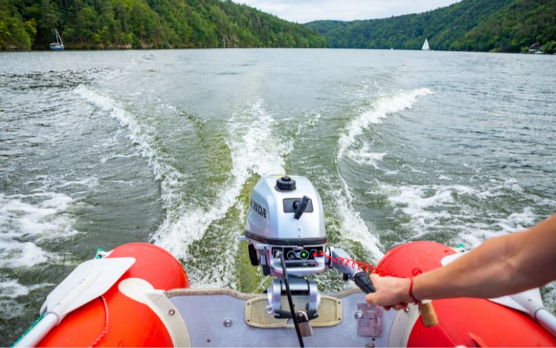 boat driver is controlling an outboard motor on an inflatable boat
