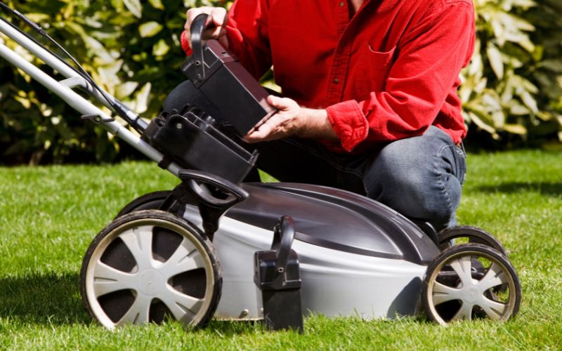 Man is installing a lawnmower battery