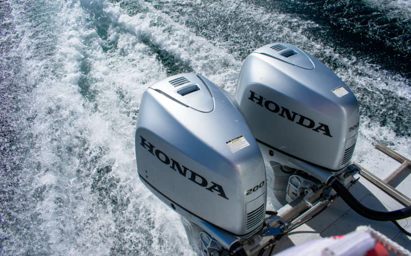Two Honda outboard motors running at high speed on the water