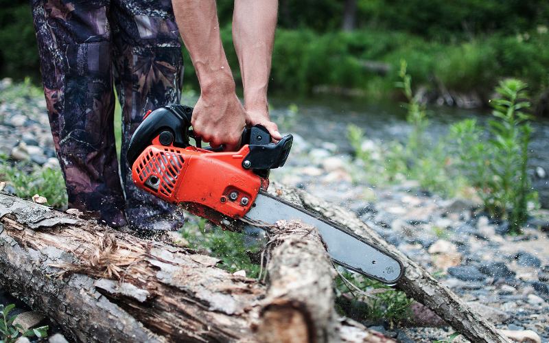 a man is using 2 stroke engine chainsaw to cut the trunk