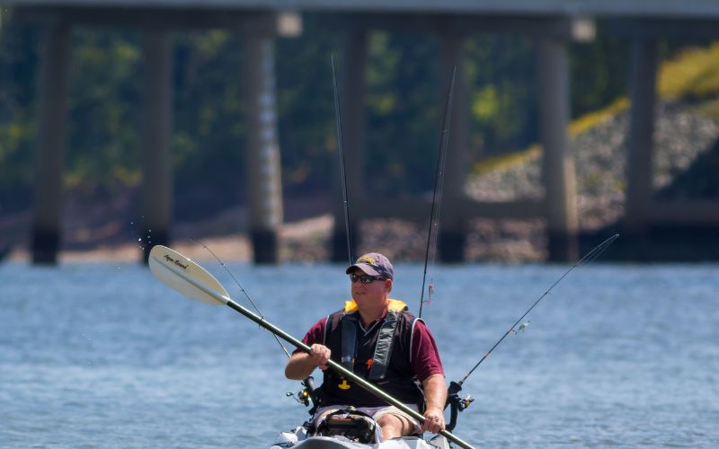 man is on his fishing and kayaking on a sunny day