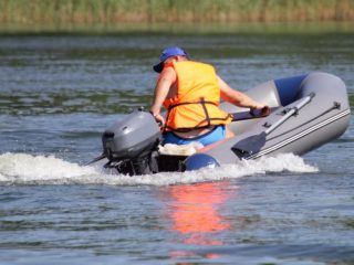 man driving an inflatable boat with small outboard motor